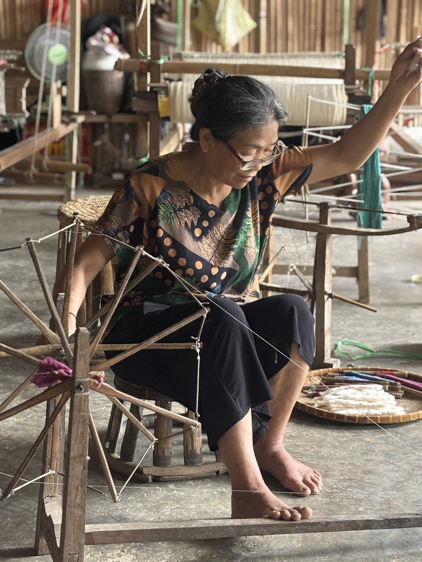 Cô Bích spinning silk at a wooden wheel in Hoa Tiến