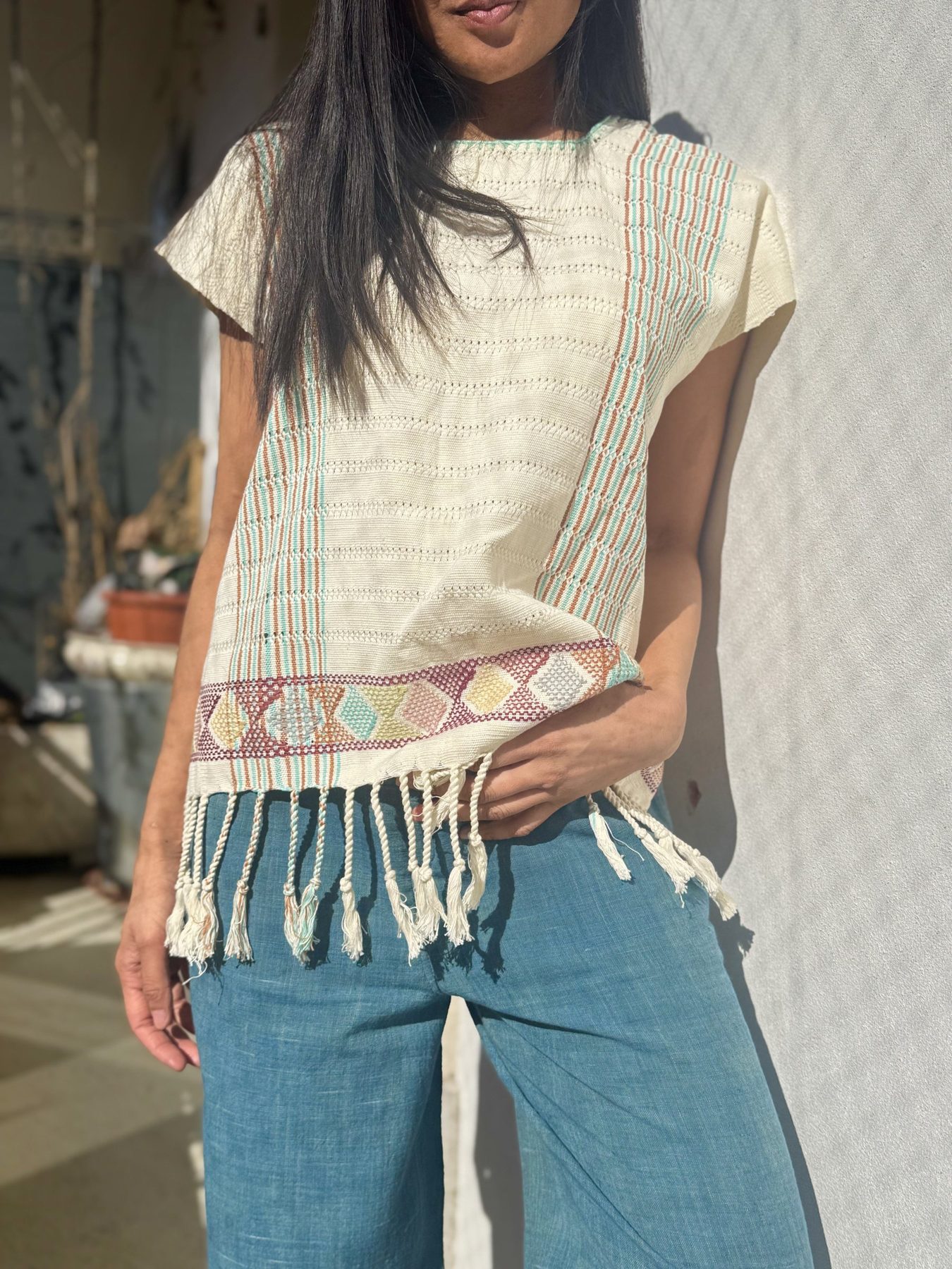 A Nichim huipil in undyed cotton — openwork stripes in terracotta and jade, a band of coloured diamonds at the hem, finished with twisted fringe